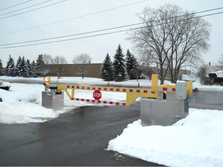 Electric drop arm surrounded by snow used to show the importance of fall and winter maintenance of active vehicle barriers.