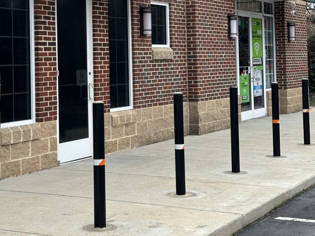 Barrier1 Tomcat S10 Bollards installed in front of a strip mall. Image is of an area that represents the topic of the blog: Protecting Your Business from Holiday Vehicular Threats.