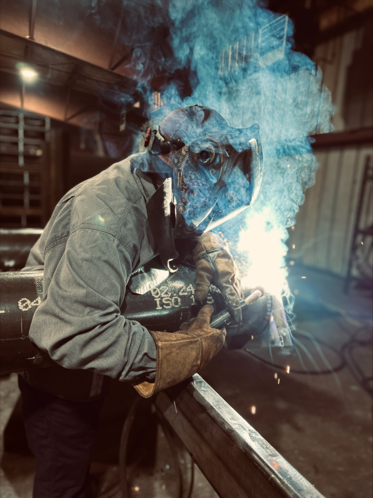 Welder welding a bollard in the shop