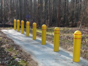 A row of yellow thermoplastic bollard covers over bollards along a path.