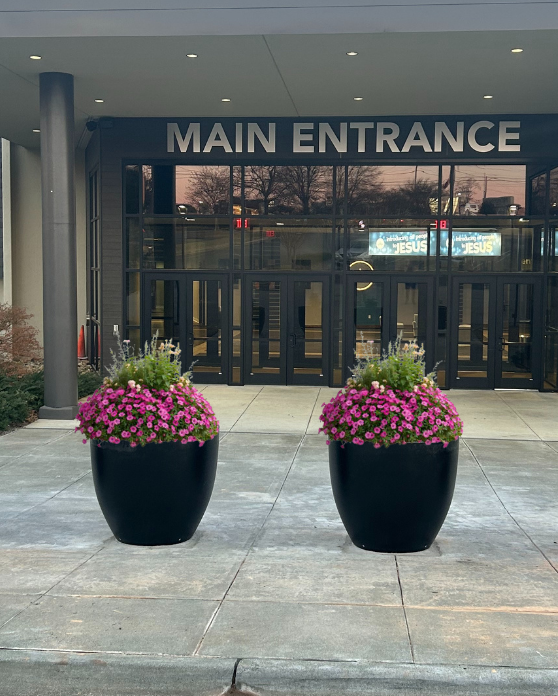 Security planter bollards with pink flowers in front of a church entrance